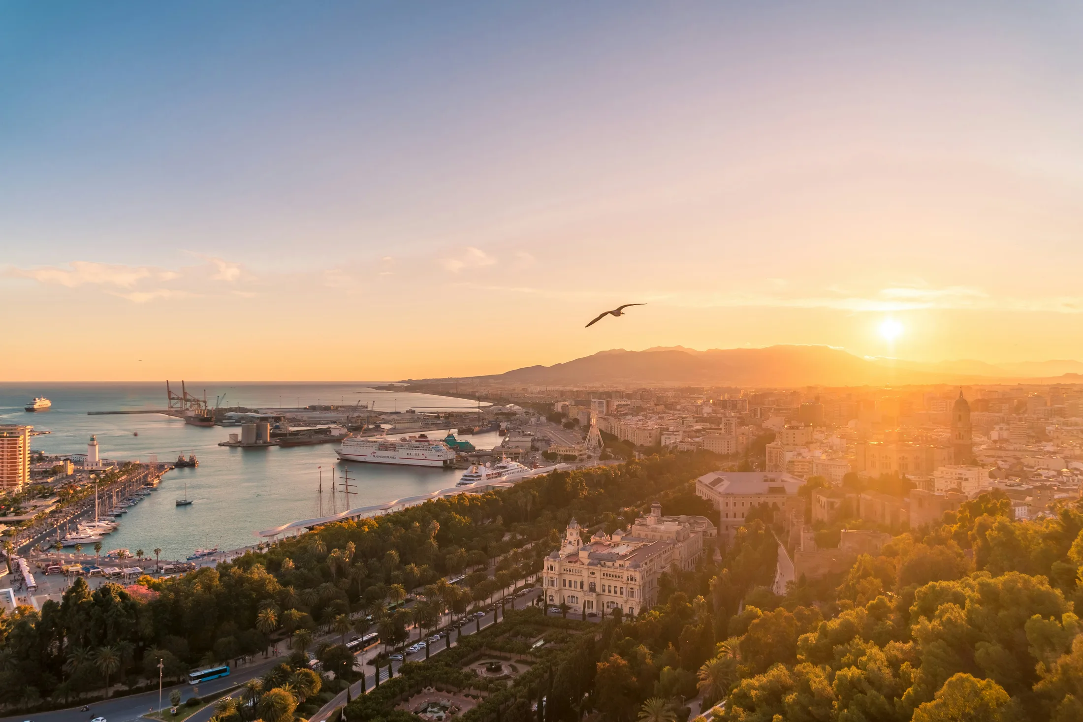 Málaga at sunset seen from above — the port, the park and the city glowing in golden light